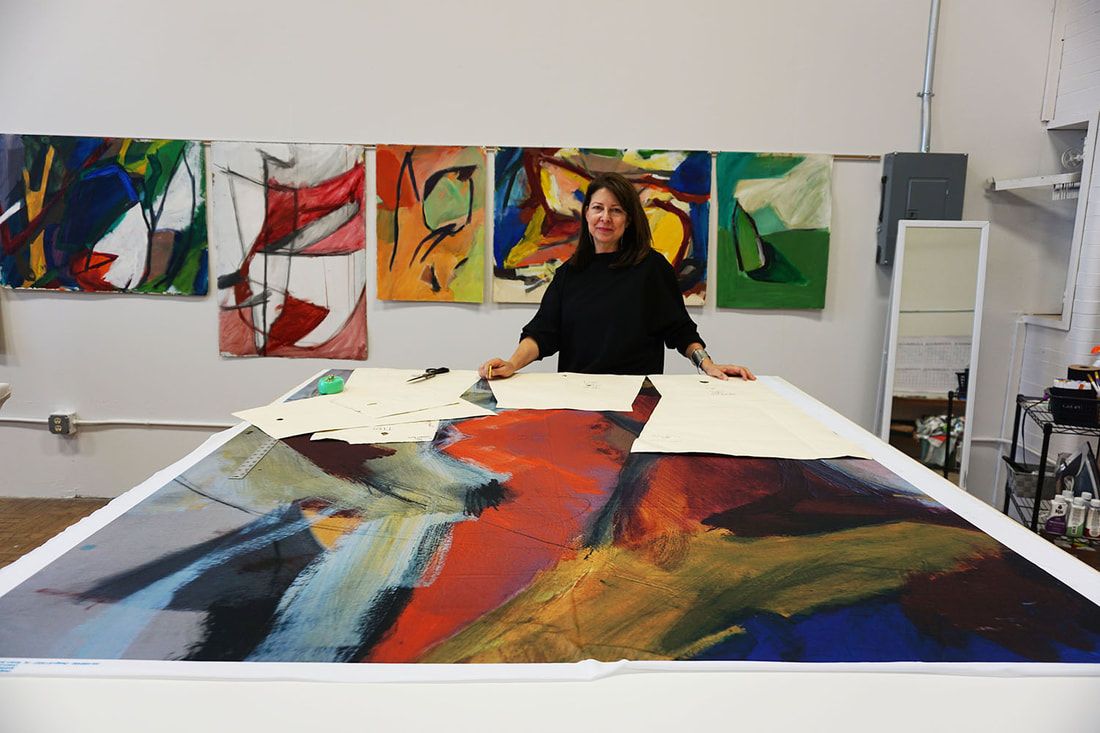 Andrea Geer in her studio with one of her paintings.